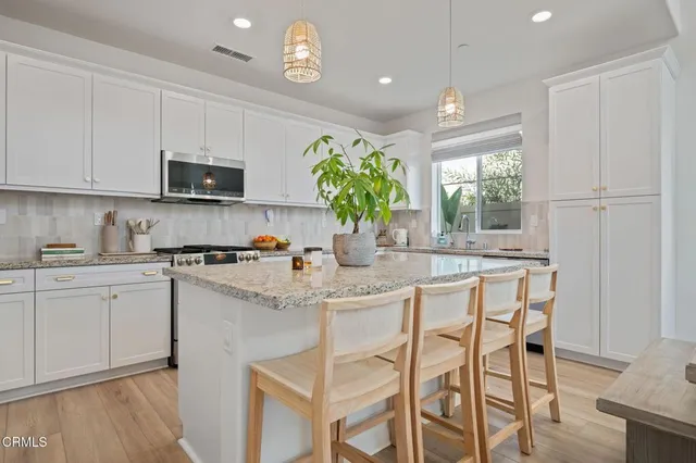 a kitchen with stainless steel appliances granite countertop white cabinets a sink and a stove