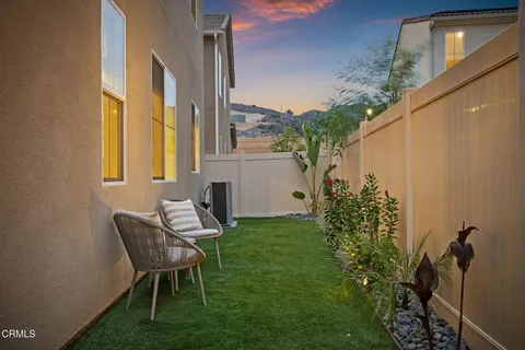 a view of a chair and table in backyard of the house