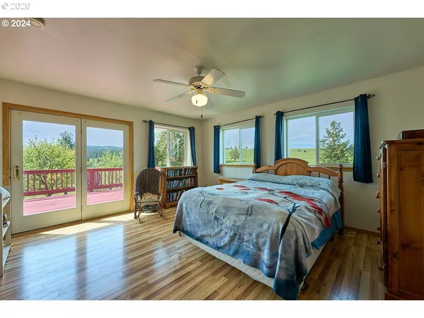 a bedroom with a large bed a large window with wooden floor