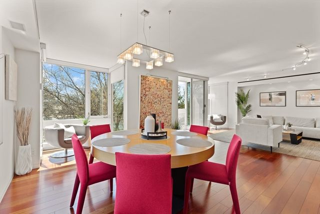 a view of a dining room and livingroom with furniture wooden floor a rug a flat screen tv a painting and a chandelier