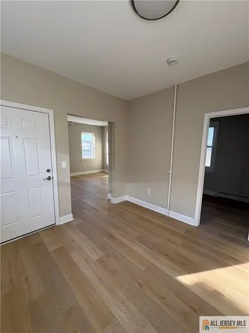 a view of an empty room with wooden floor and closet