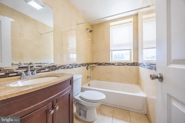 a bathroom with a granite countertop sink toilet a mirror and bathtub