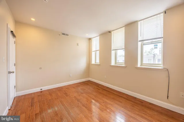 a view of empty room with wooden floor and fan