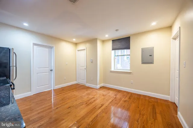 a view of an empty room with wooden floor and a window