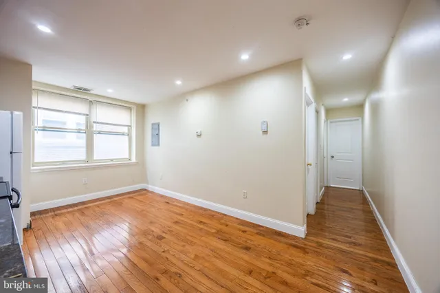 a view of an empty room with wooden floor and a window