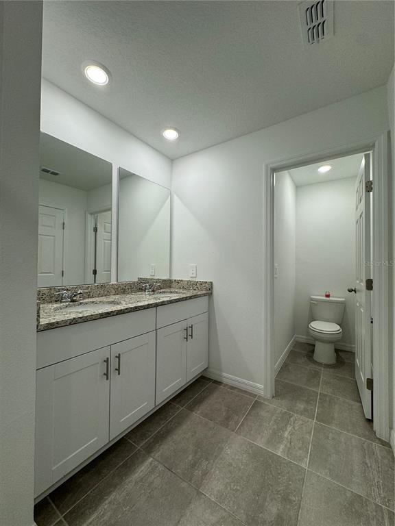 4346 Restful Fallow Cove St. Cloud, FL 34772 - Photo 17 of 20 a spacious bathroom with a granite countertop sink a toilet and a mirror