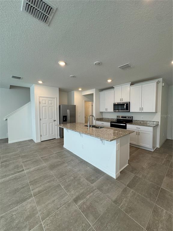 4346 Restful Fallow Cove St. Cloud, FL 34772 - Photo 2 of 20 a large white kitchen with stainless steel appliances granite countertop a sink and cabinets
