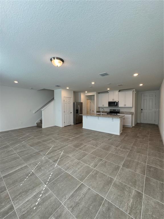 4346 Restful Fallow Cove St. Cloud, FL 34772 - Photo 3 of 20 a large white kitchen with kitchen island a stove a sink and a refrigerator