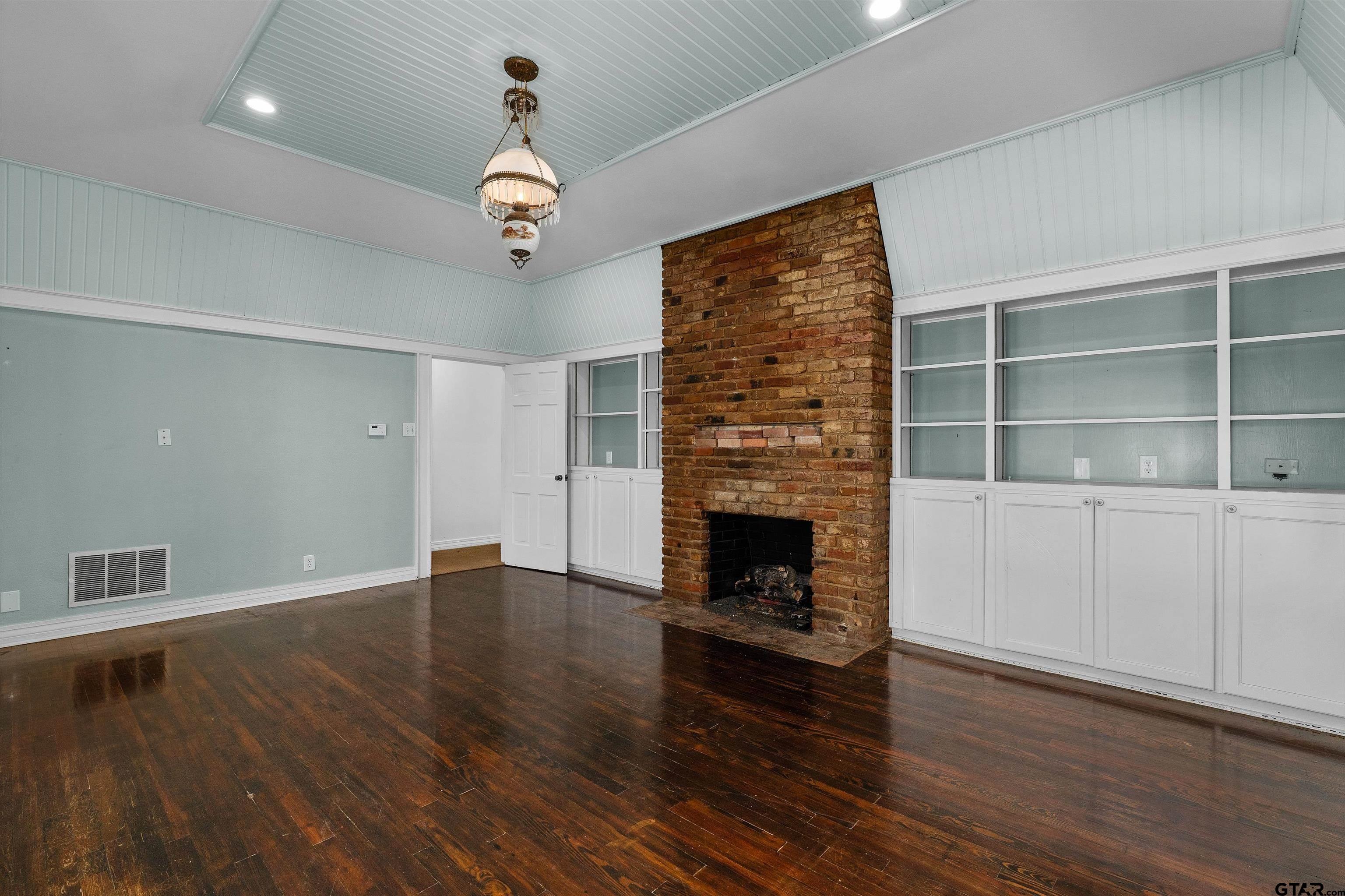 326 East Main Street Henderson, TX 75652 - Photo 15 of 35 an empty room with wooden floor fireplace and windows