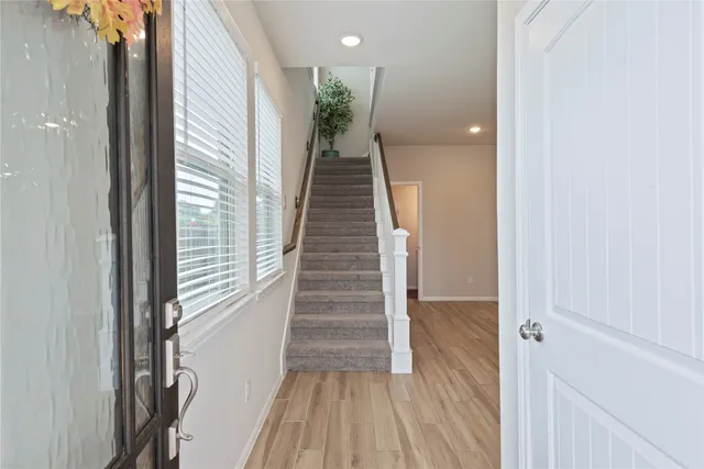 a view of a hallway with wooden floor and stairs