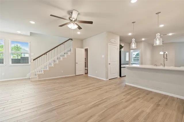 a view of an empty room with wooden floor and a ceiling fan