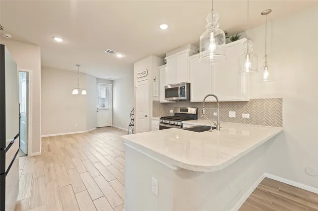 a view of a kitchen with kitchen island a sink stainless steel appliances and cabinets