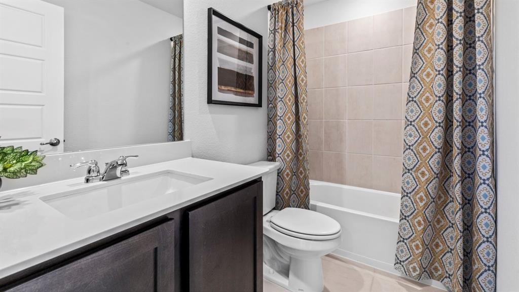 500 Range Road Caddo Mills, TX 75135 - Photo 4 of 35 Bathroom featuring a white integrated sink with chrome faucet, dark wood-finish vanity cabinetry, a built-in bathtub with a tiled surround, and a wall-mounted toilet