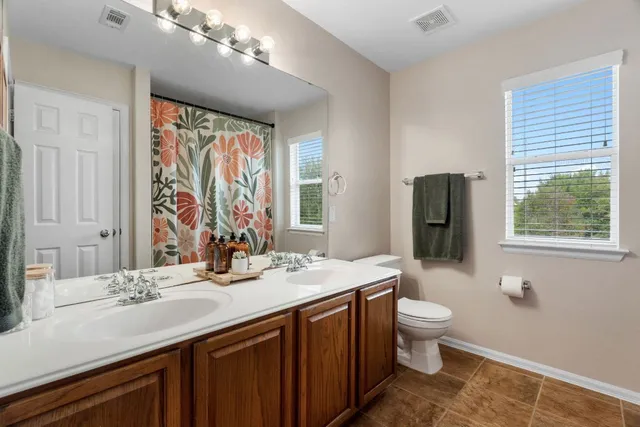 a bathroom with a double vanity sink toilet and a mirror