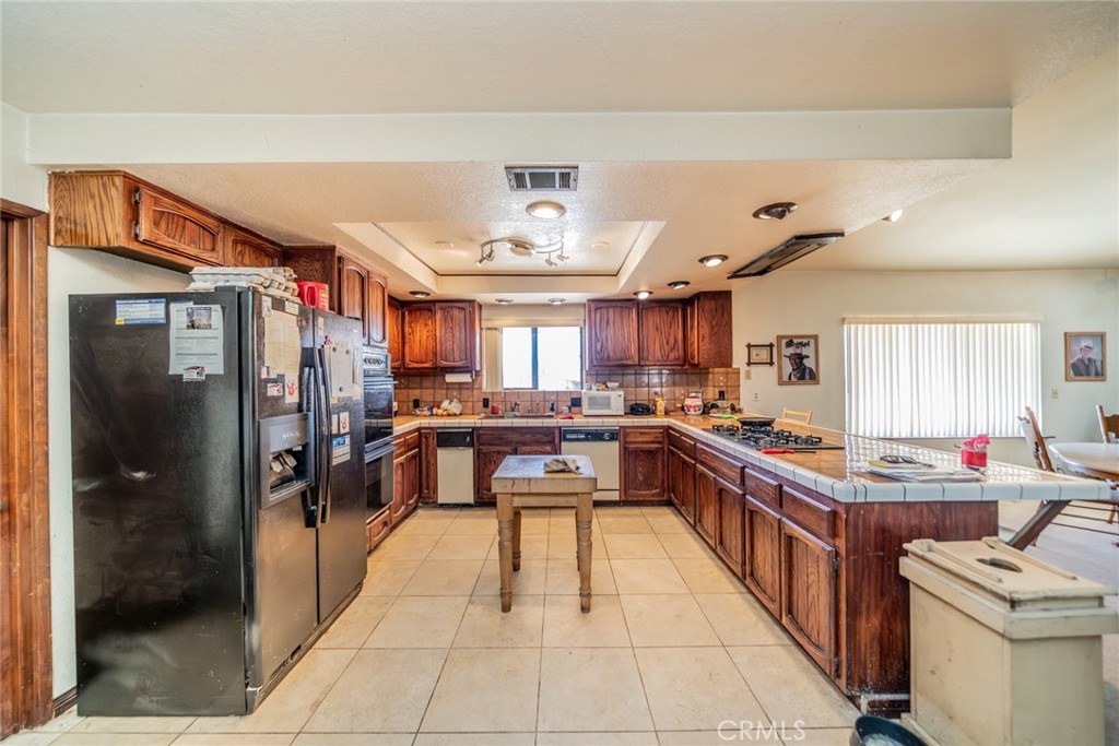 18080 Manitou Road Apple Valley, CA 92307 - Photo 3 of 43 a kitchen with stainless steel appliances granite countertop a refrigerator a sink dishwasher a stove and a dining table with wooden floor
