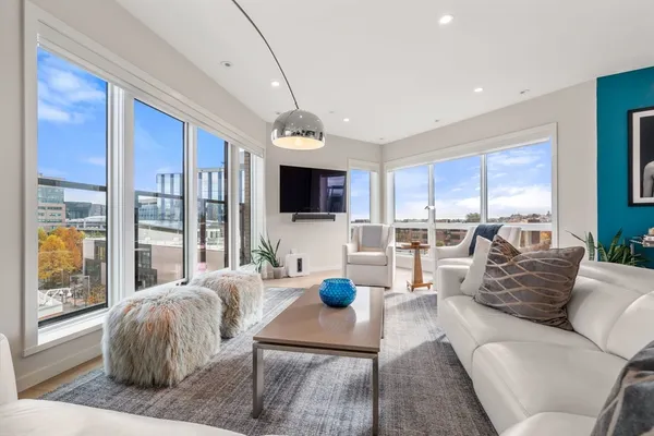 a living room with furniture flat screen tv and large windows