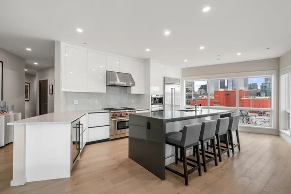 a kitchen with stainless steel appliances granite countertop a table chairs sink refrigerator and cabinets