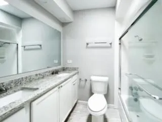 a bathroom with a granite countertop toilet sink and mirror