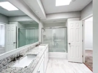 a bathroom with a granite countertop sink a mirror and a bathtub