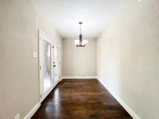 a view of a hallway with wooden floor and chandelier