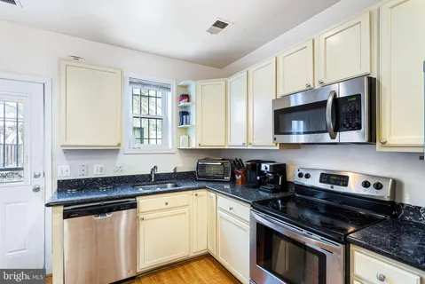 a kitchen with stainless steel appliances granite countertop a sink a stove a microwave and wooden cabinets