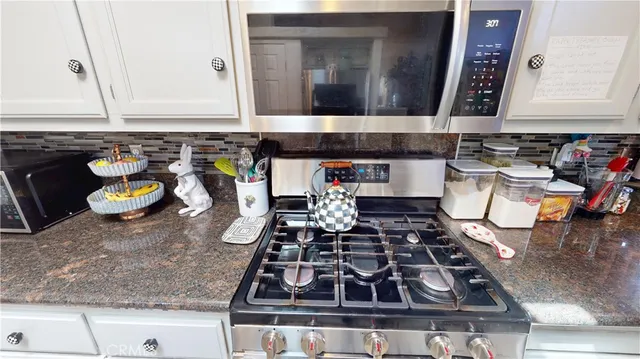 a kitchen with a stove and a white wooden cabinets