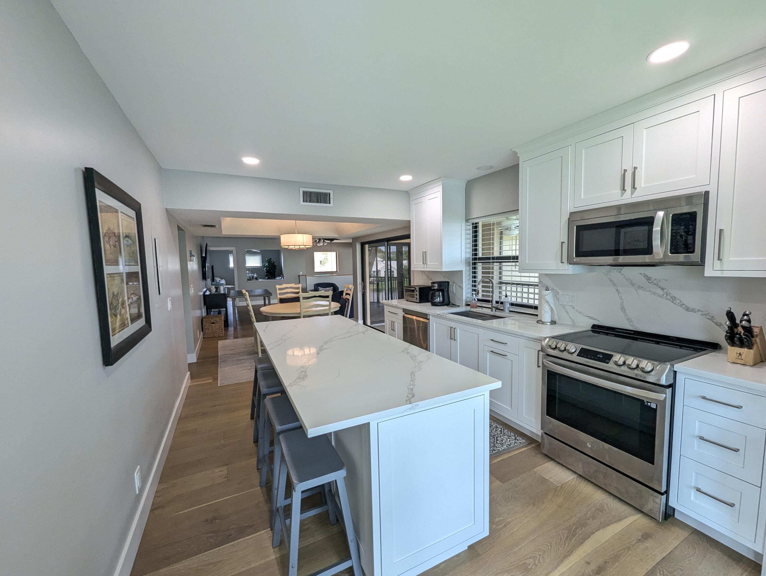 17081 Waterbend Drive, Unit 228 Jupiter, FL 33477 - Photo 10 of 21 a kitchen with stainless steel appliances a stove a sink a microwave a refrigerator white cabinets and wooden floor