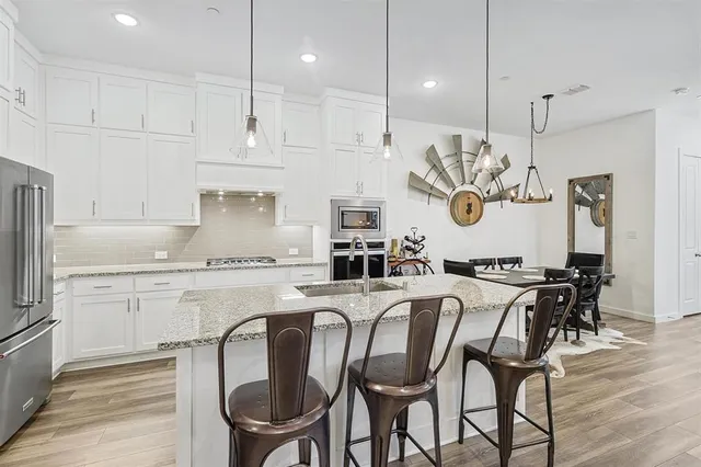 a kitchen with stainless steel appliances granite countertop a kitchen island a stove a table and chairs in it