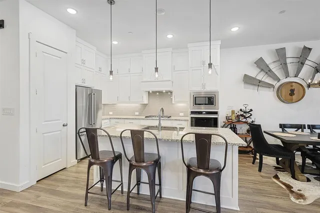 a kitchen with stainless steel appliances granite countertop a table chairs stove and refrigerator