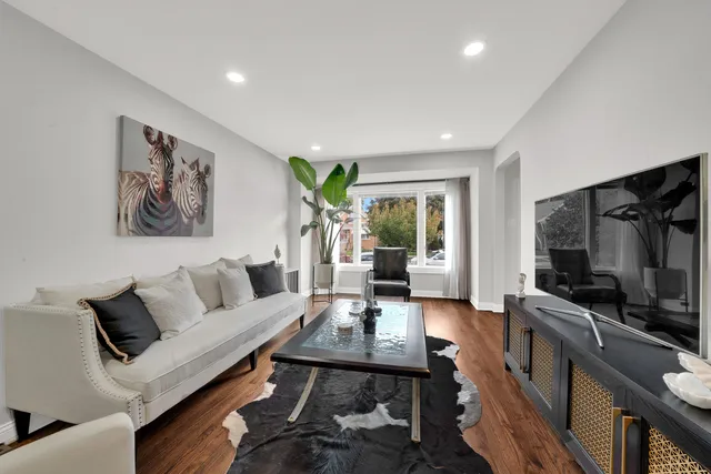 a living room with furniture a flat screen tv and a refrigerator