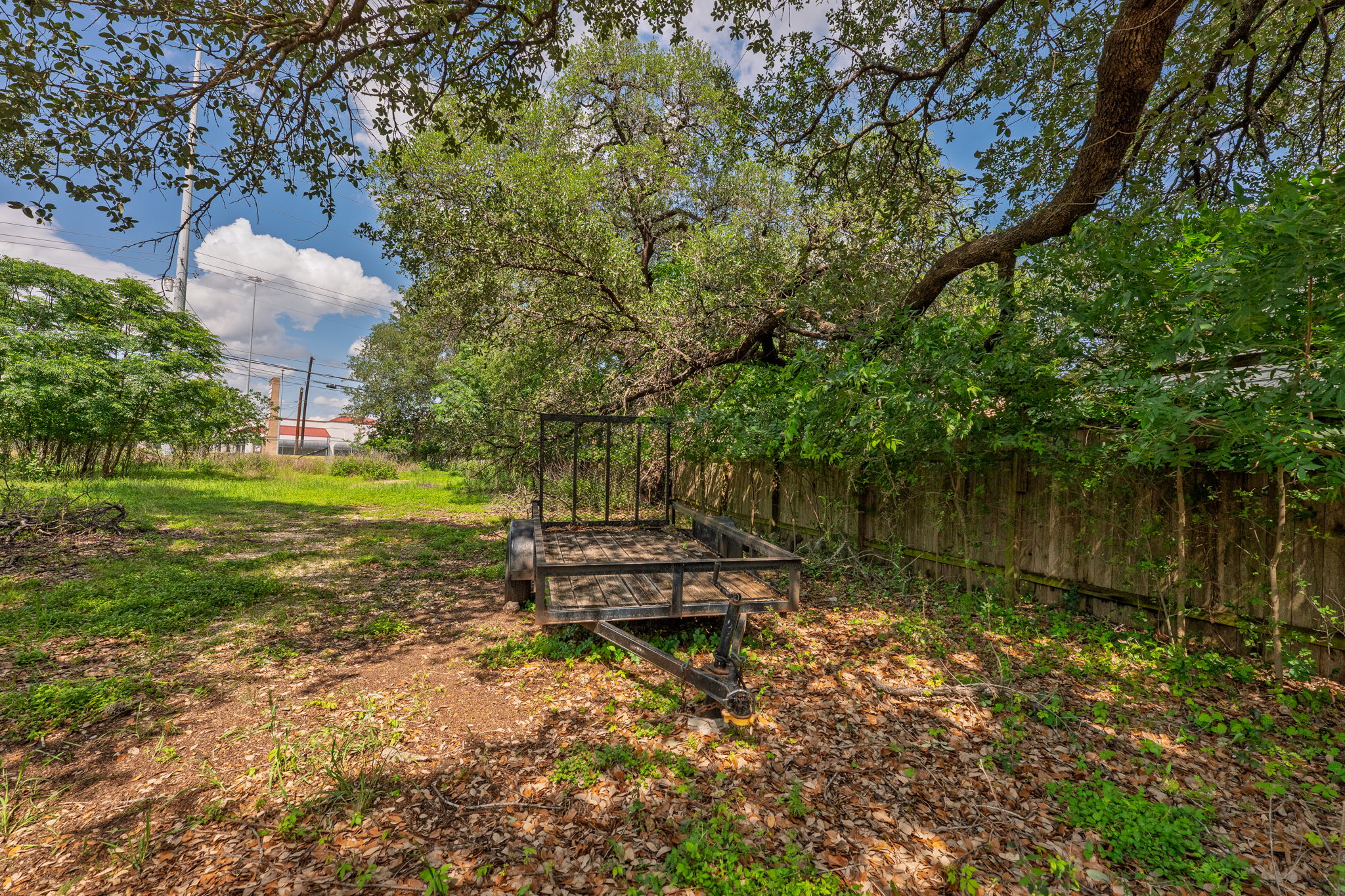 12182 Jollyville Road Austin, TX 78759 - Photo 14 of 25 Spacious outdoor area featuring mature trees, partial wood fencing, and natural ground cover