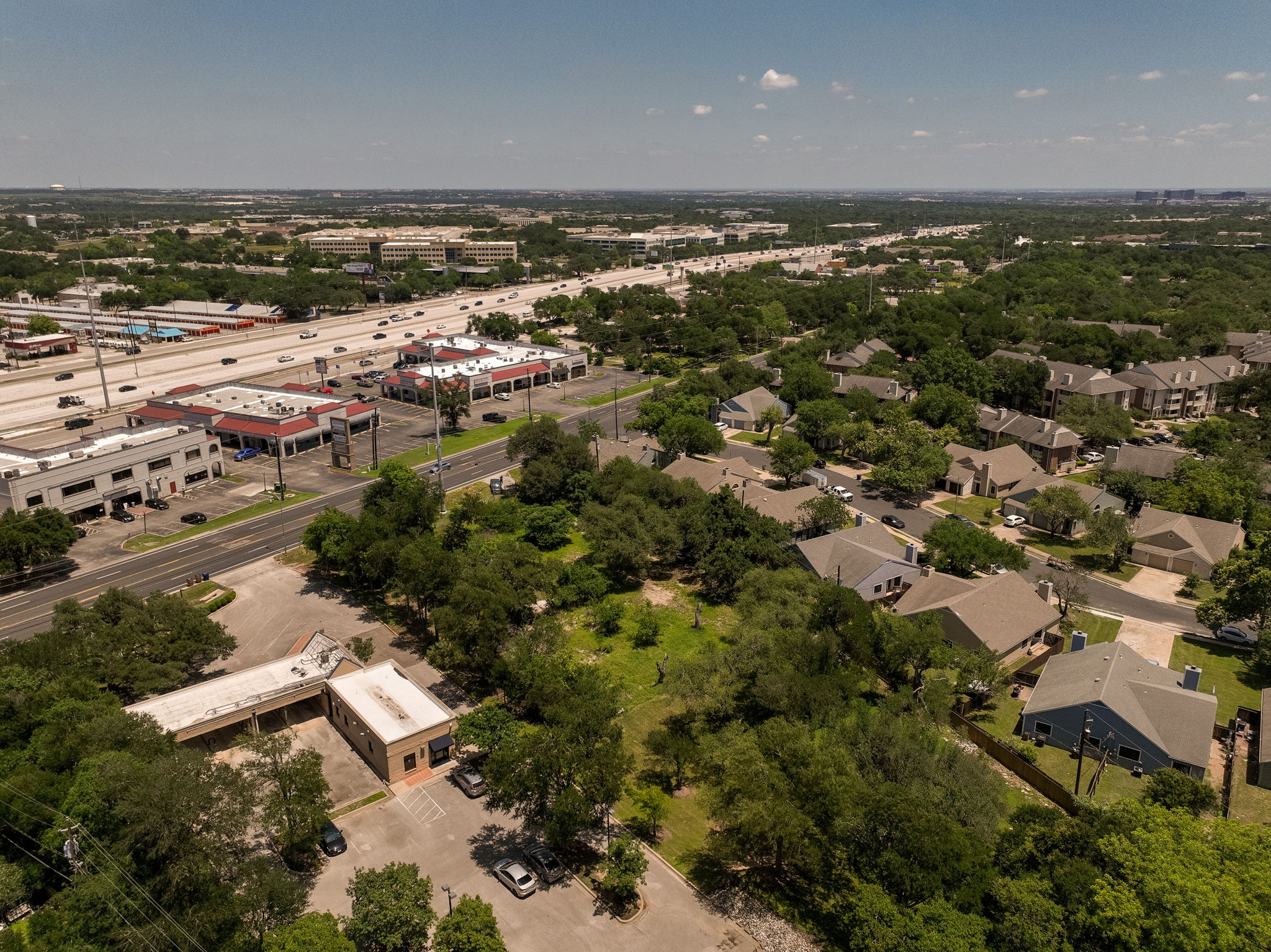 12182 Jollyville Road Austin, TX 78759 - Photo 23 of 25 Aerial perspective showcasing a commercial building with ample parking, surrounded by mature trees