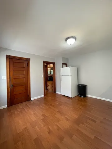 a view of an empty room with window and wooden floor