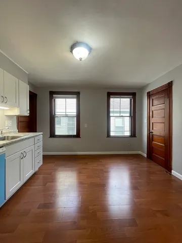 a view of empty room with wooden floor and refrigerator