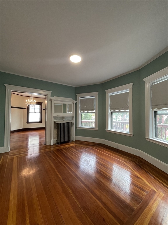 71 Mayfield Street, Unit 2 Boston, MA 02125 - Photo 2 of 33 an empty room with wooden floor fireplace and windows