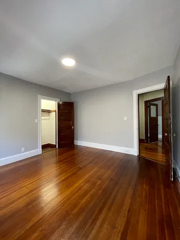 an empty room with wooden floor and closet and window