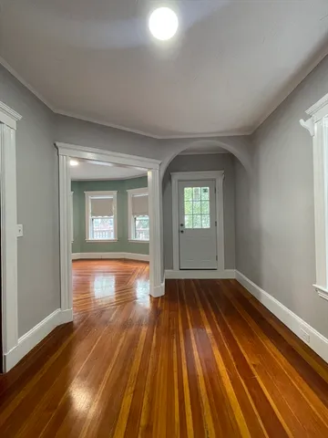 a view of empty room with window and wooden floor