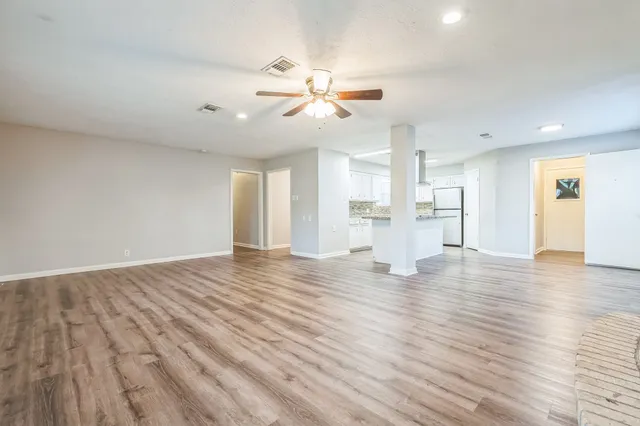 a view of an empty room with window and wooden floor