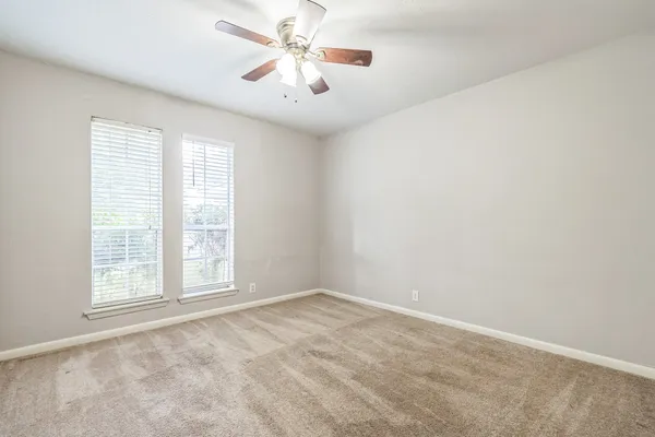 an empty room with windows and fan
