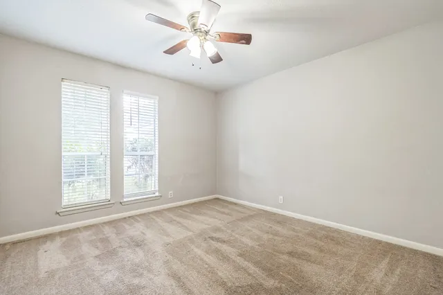 an empty room with windows and fan