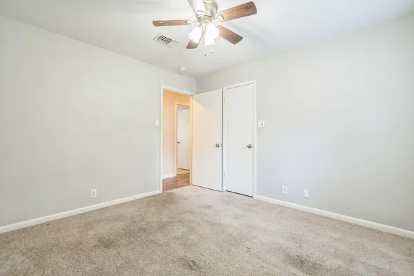 an empty room with chandelier fan and ceiling fan