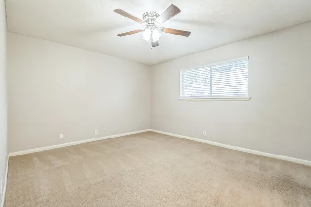 an empty room with a window and a fan