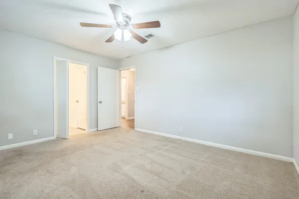 an empty room with chandelier fan and windows