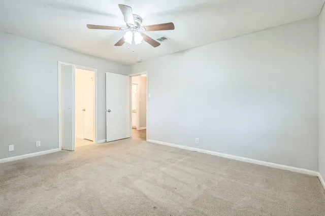an empty room with chandelier fan and windows