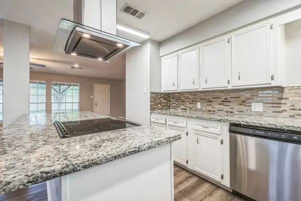 a kitchen with granite countertop a sink a stove and cabinets