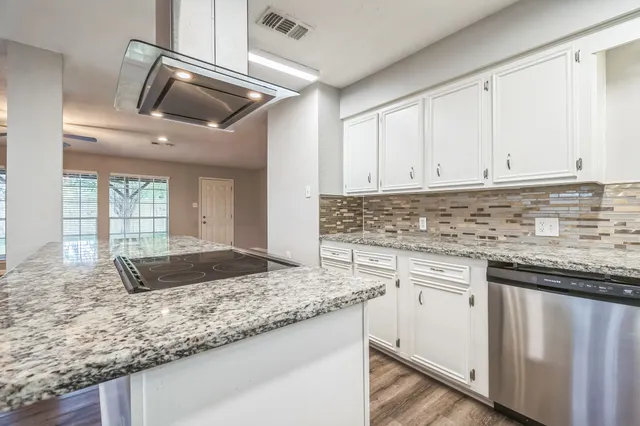 a kitchen with granite countertop a sink a stove and cabinets