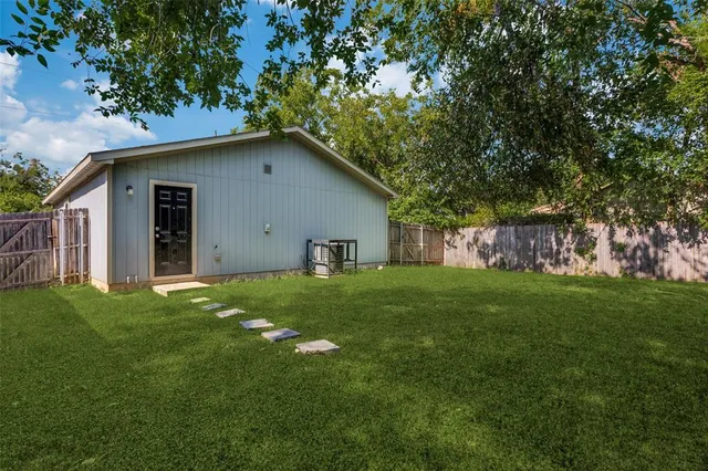 a backyard of a house with plants and large tree