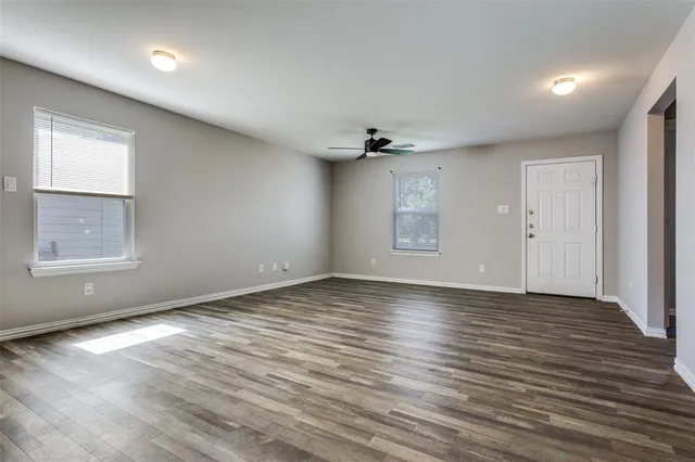 an empty room with wooden floor chandelier and windows