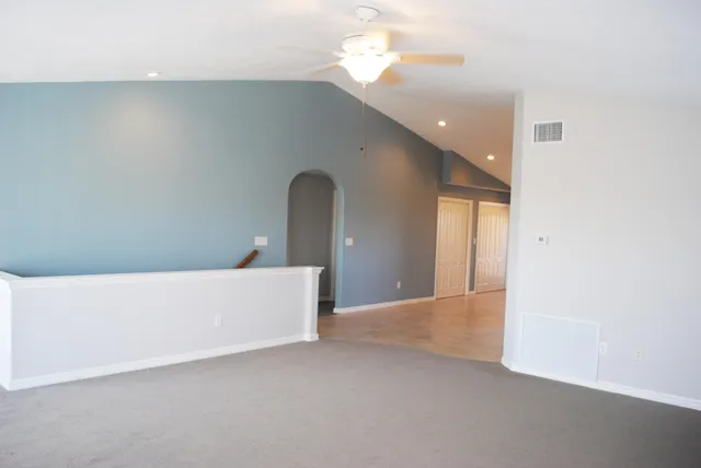 a view of an empty room with a chandelier fan