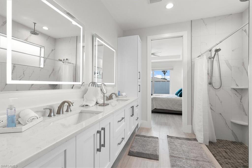 734 109th Avenue North Naples, FL 34108 - Photo 11 of 34 a en suite bathroom with a double vanity sink a mirror and a shower